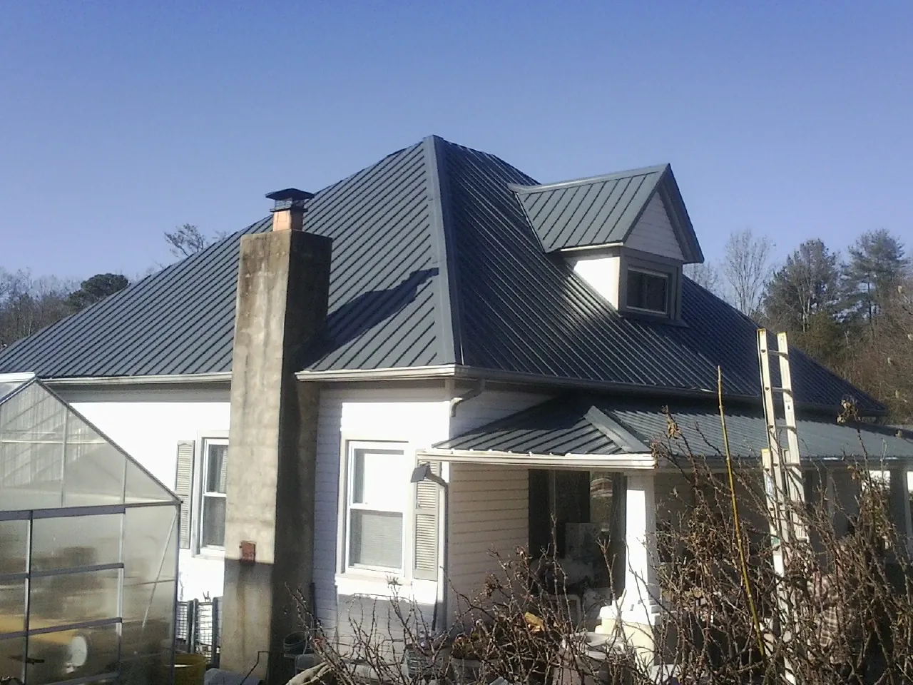 Dark blue standing seam metal roof on a white farmhouse with dormer — Slate & Tile Roof Repair by Roofing Brothers in San Ramon