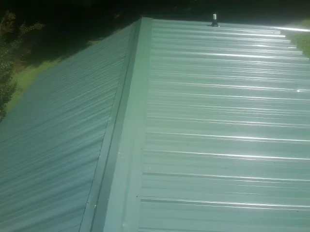 New green metal panels meeting at the ridge of a roof — Flat Roof Repair work by our crew in San Ramon