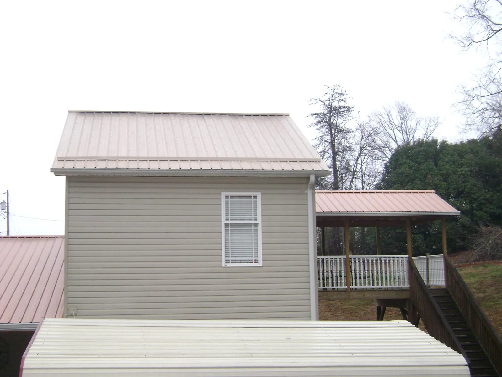 Tan metal roofs on a two story addition and attached porch, from a Roof Replacement job in San Ramon