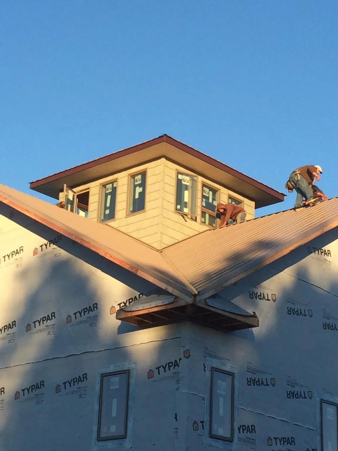 Roofers working around a rooftop cupola on a new metal roof at sunset — Roof Waterproofing in San Ramon by Roofing Brothers
